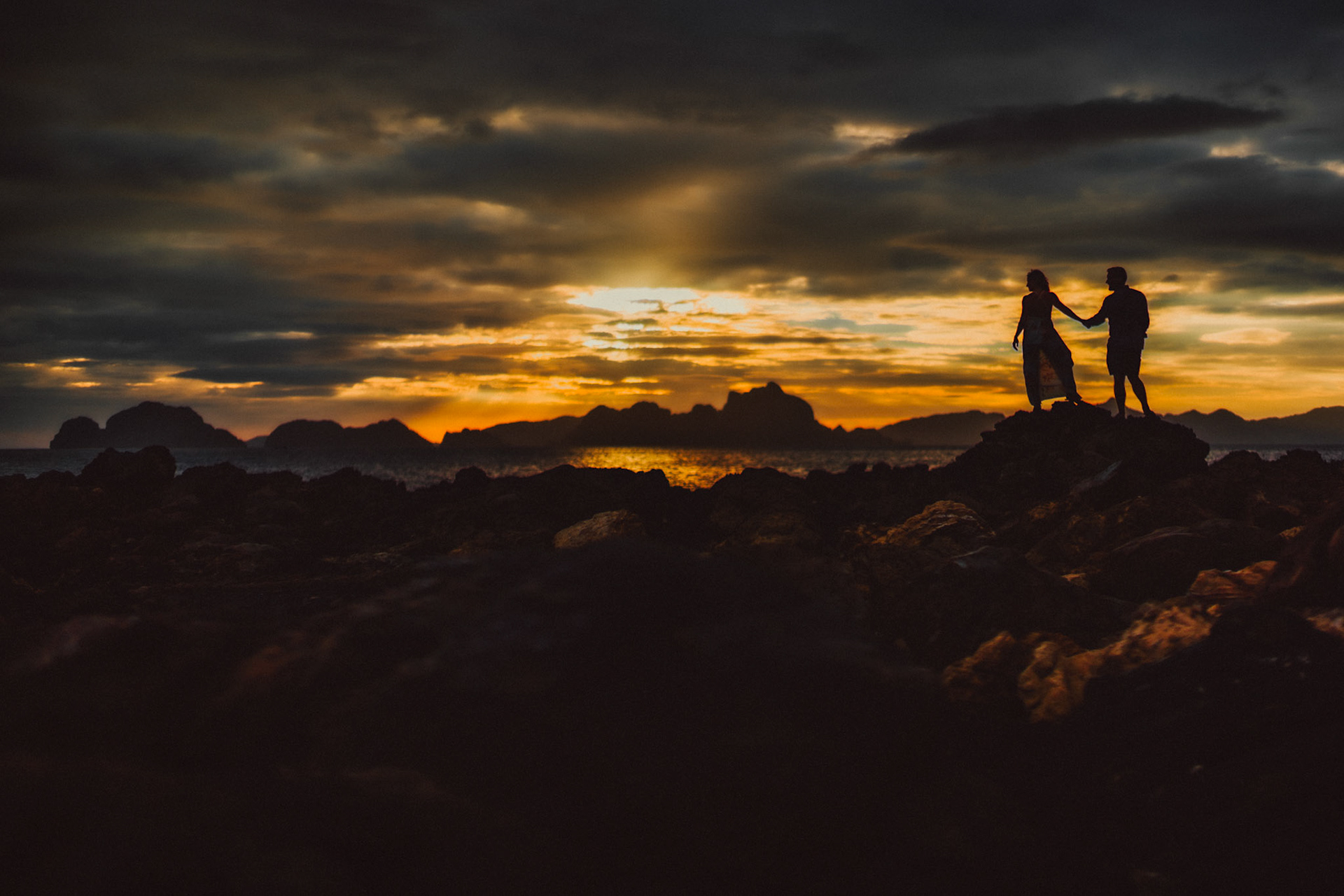 Sunset couple silhouettes with moody tones in Las Cabanas Beach, El Nido Palawan, Philippines, Southeast Asia, March 2019, Sony A7III.