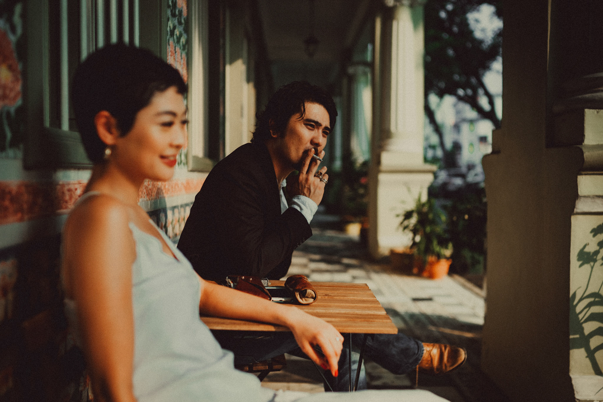A Japanese couple sharing a lighthearted moment in a sunlit corridor with Peranakan details, from Ibuki and Emi's artsy moody engagement shoot, Pertain Road, Little India, Singapore, October 2015, Sony A7S.