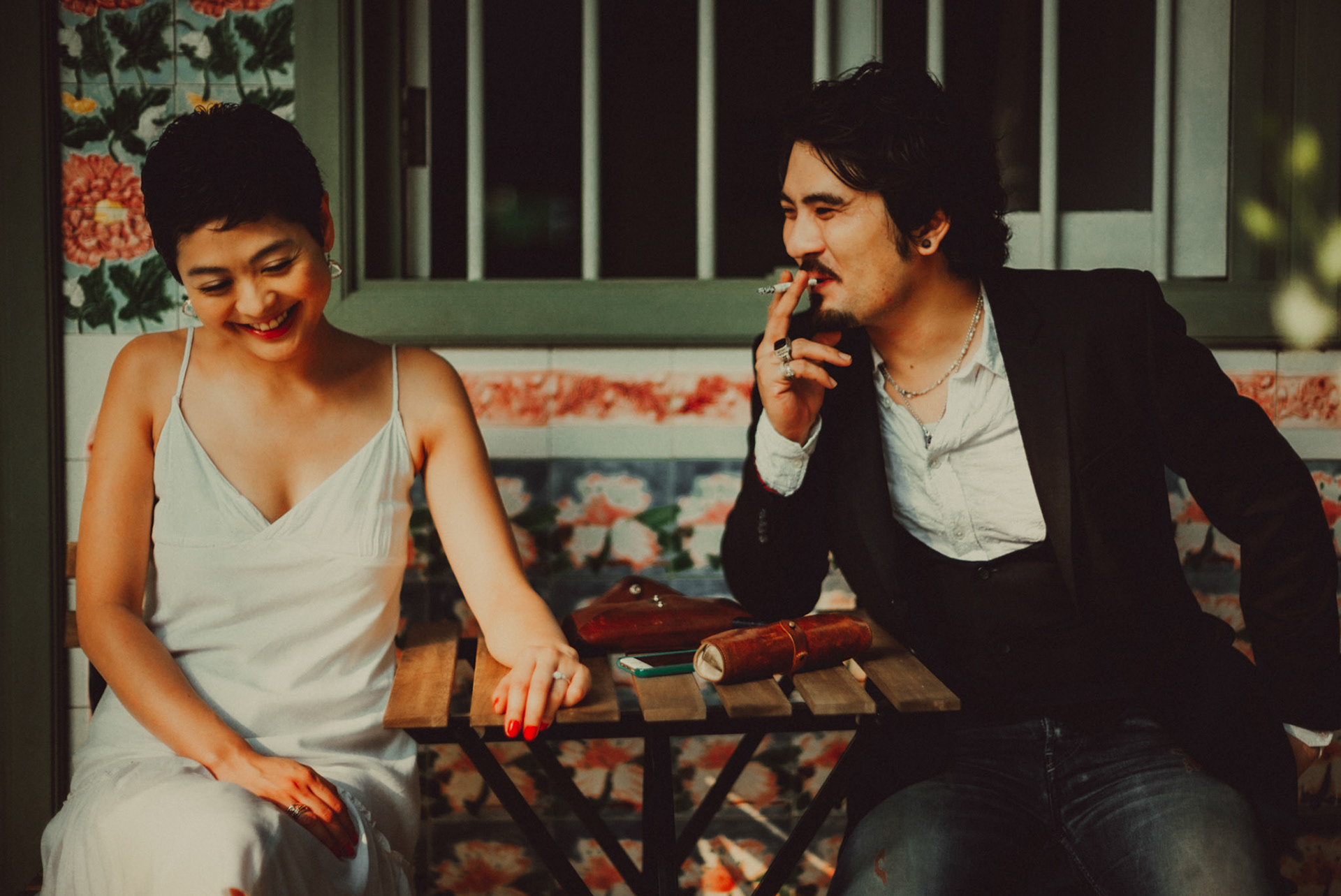 A Japanese couple sharing a lighthearted moment in a sunlit corridor with Peranakan details, from Ibuki and Emi's candid chill engagement shoot, Pertain Road, Little India, Singapore, October 2015, Leica M.