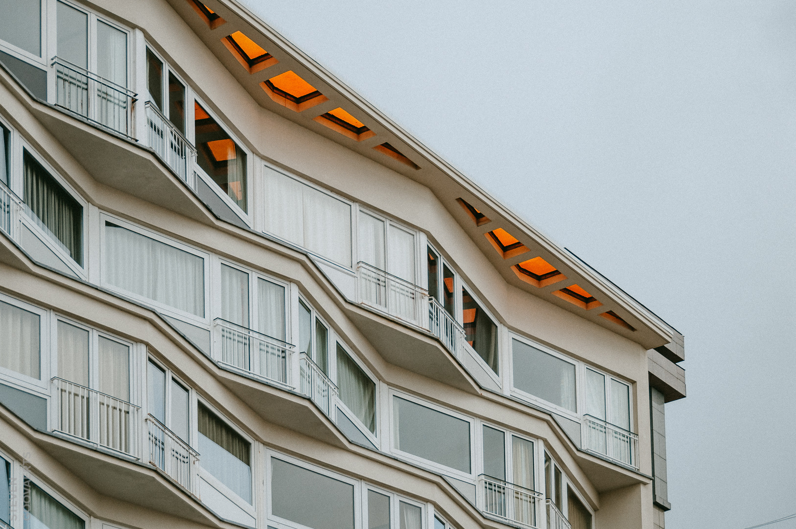 Laat ons wat creativiteit in het gebouw steken, dacht deze architect. De gevel zigzagt als de golven van de zee maar dan wel in rechte lijnen. En voor de gelukzakken op de bovenste verdieping: een oranje glas voor een gezellig warme gloed.