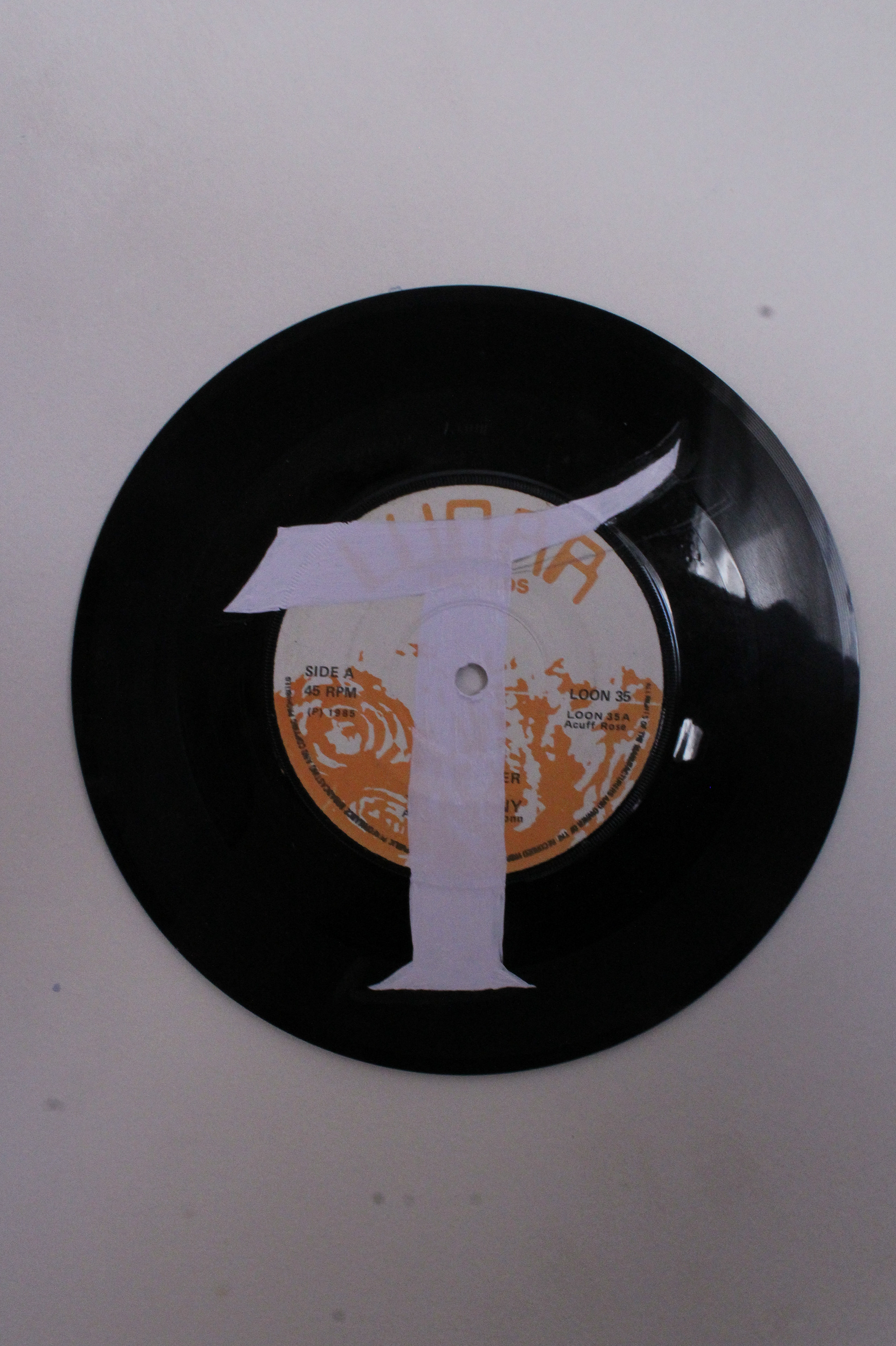 T painted on a vinyl to represent the physical in music consumption. The T is from the cover of Live Through This by Hole