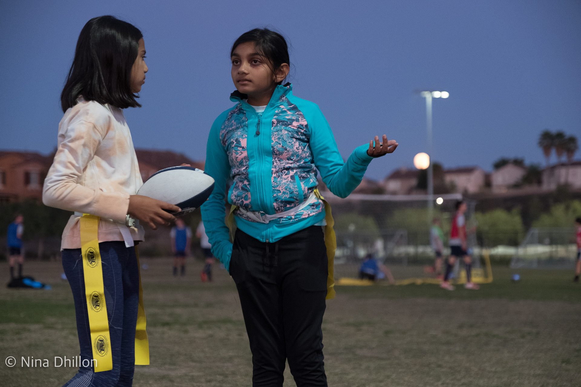 FOREGROUND & BACKGROUND: October 20, 2021. Pacific Highlands Park, San Diego. Football plays are being made, while soccer practice continues in the back. 1/125 sec at f/2.8 ISO 2500.