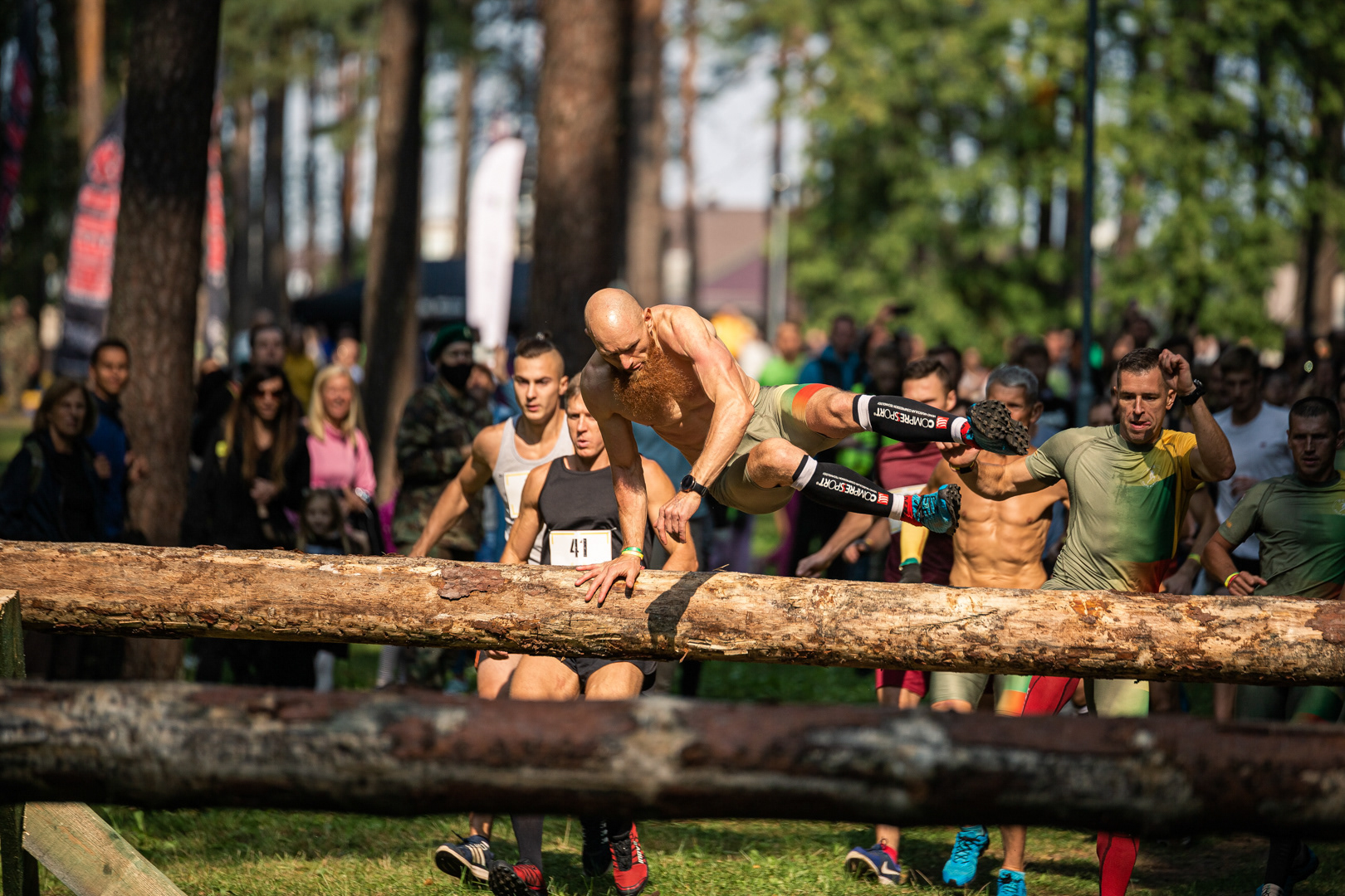 Sportininkas įveikia kliūtį OCR bėgimo varžybų metu