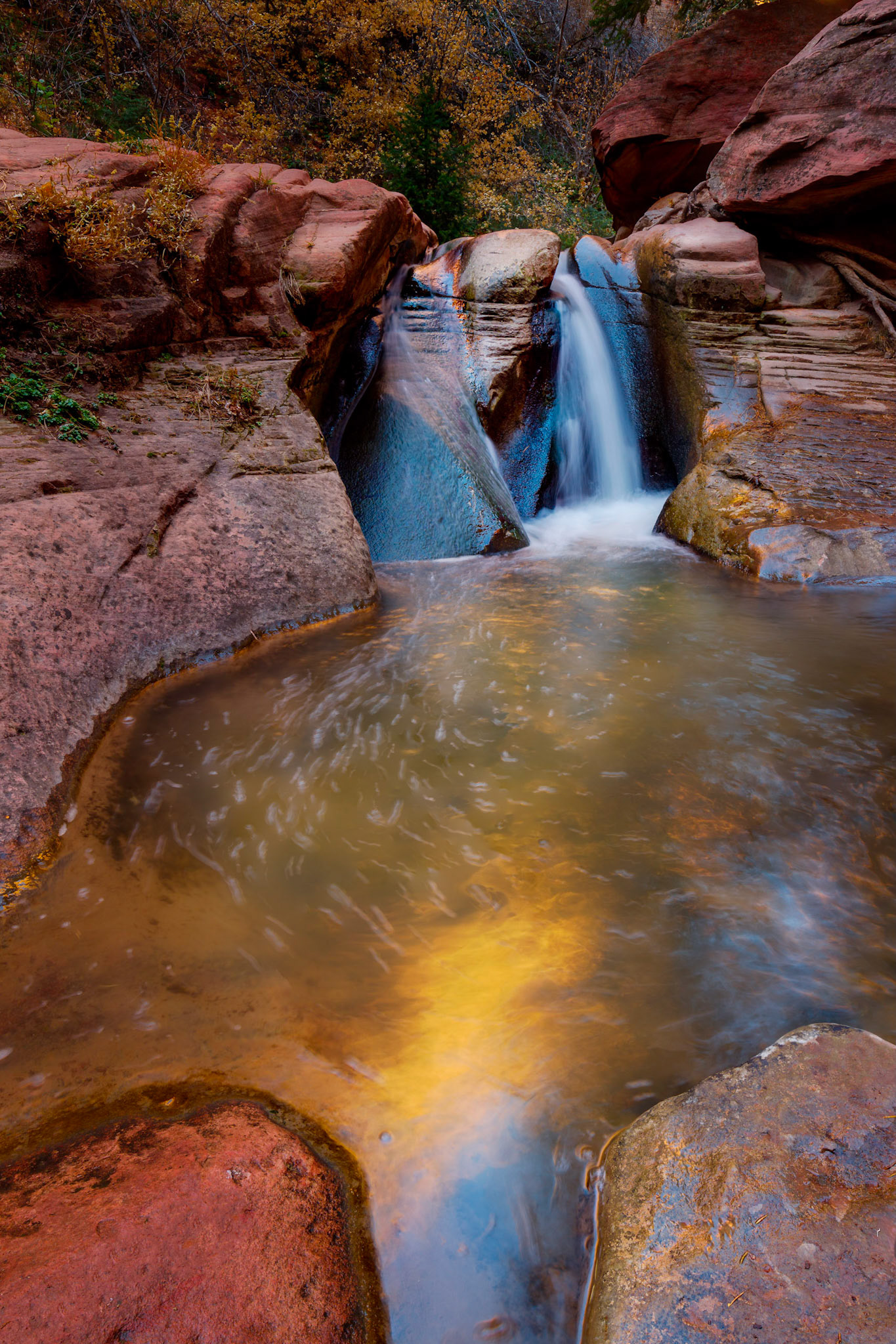 A small waterfall in one of the wider parts of the Kanarraville canyon.The orange reflection in the water is from the rocks behind the waterfall that were in full sunlight.  The blue reflection in the rocks by the waterfall were from the sky behind me.Kanarraville, UtahNovember 14, 2017PENTAX K-1, HD PENTAX-D FA 15-30mm F2.8ED SDM WRISO 100 16 mm  0.6 sec at ƒ / 18