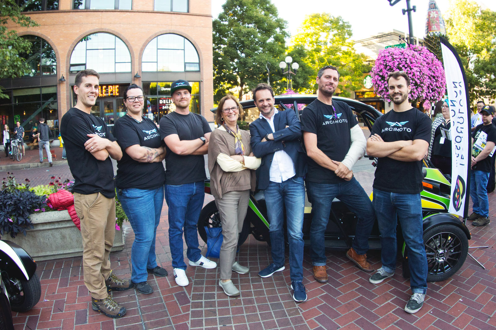 Mayor Lucy Vinis poses with Arcimoto team and vehicle on downtown street corner