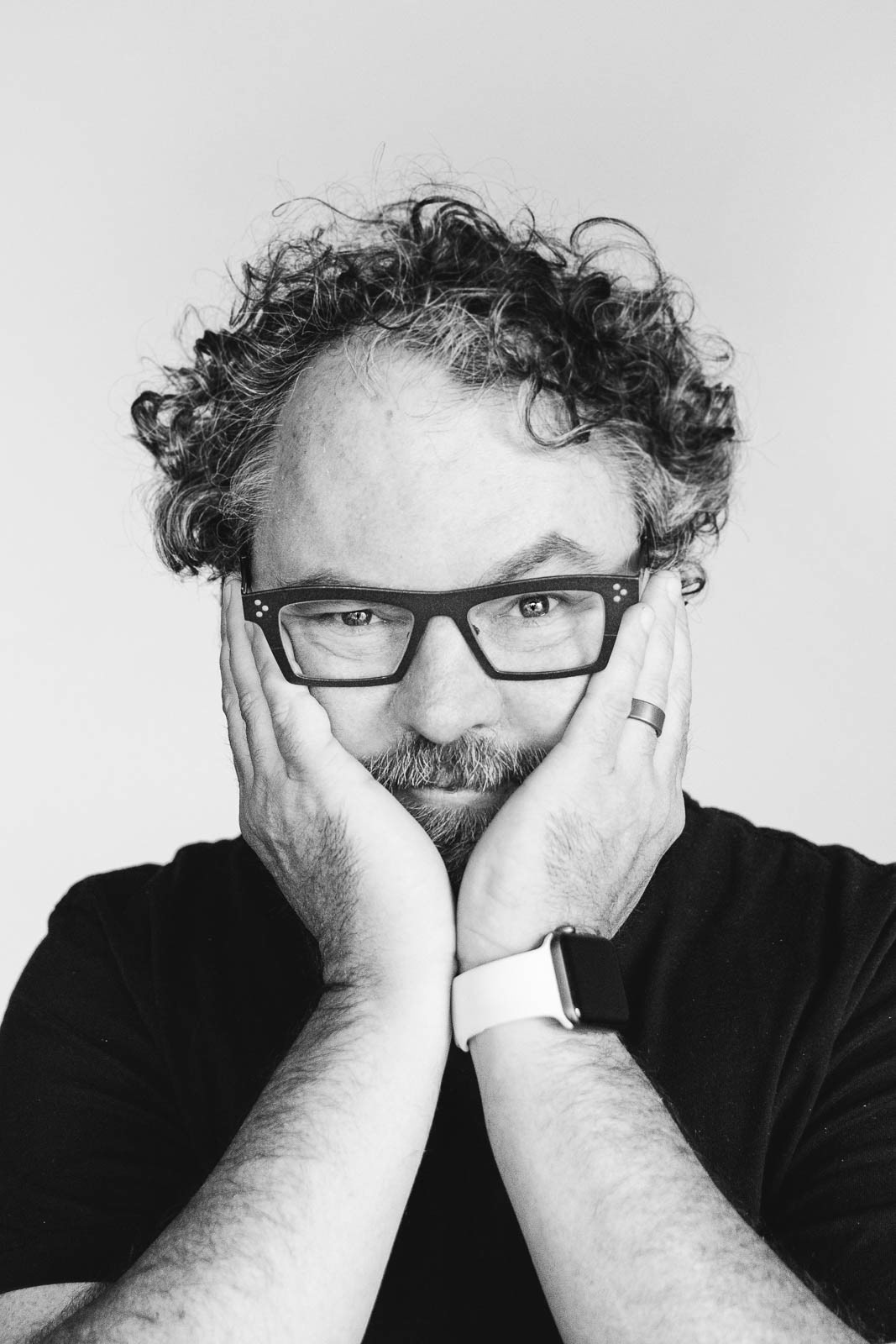 Studio headshot of company executive holding face in hands