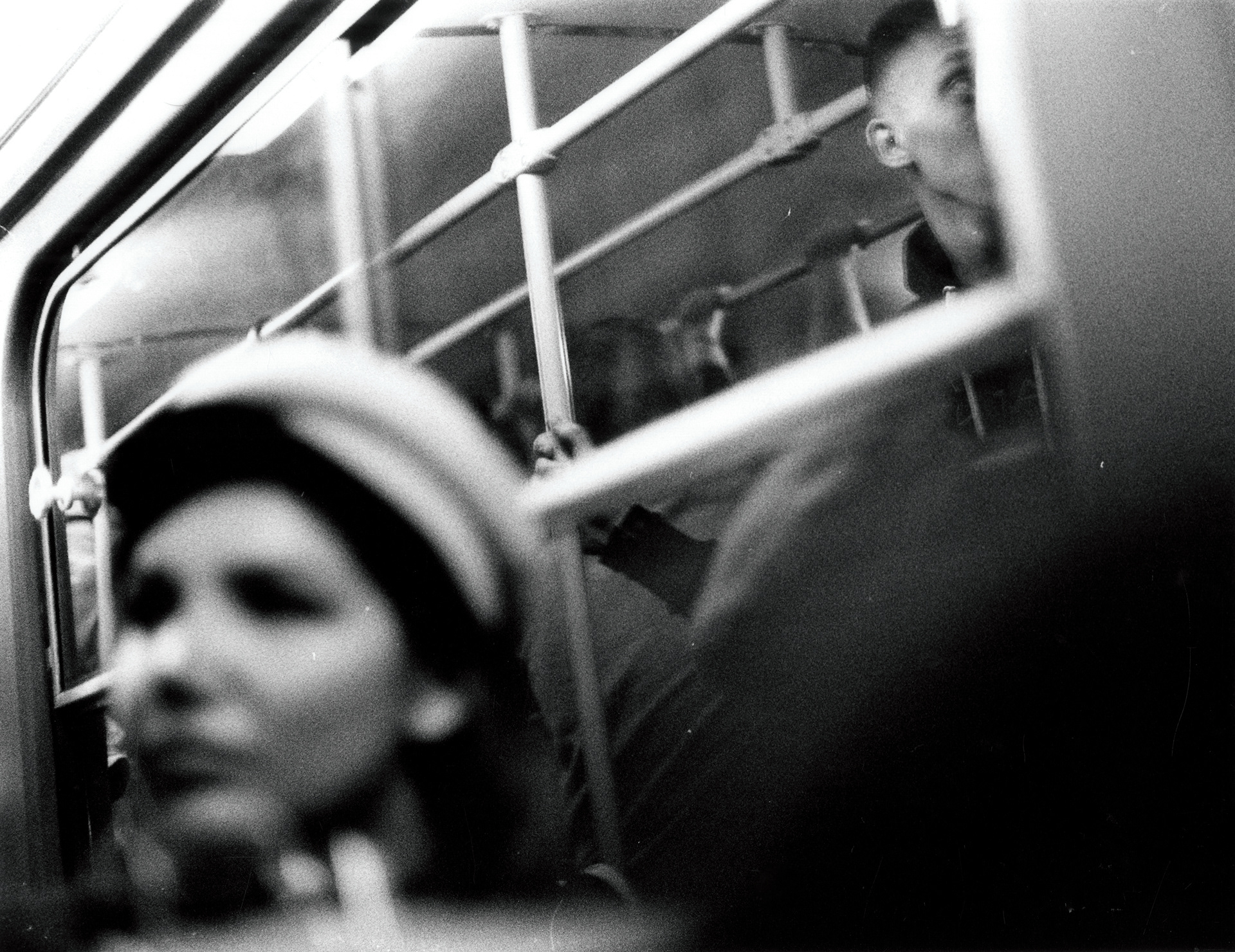 a woman is unrecognisable, out of focus while sat on a tram in Prague, in the background, in the reflection of the window, a man is half visible