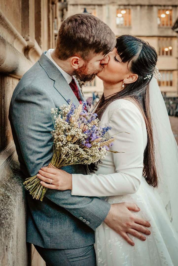 happy bride and groom kissing intimately against wall near radcliffe camera at covid wedding by photographer david lefebvre near oxford
