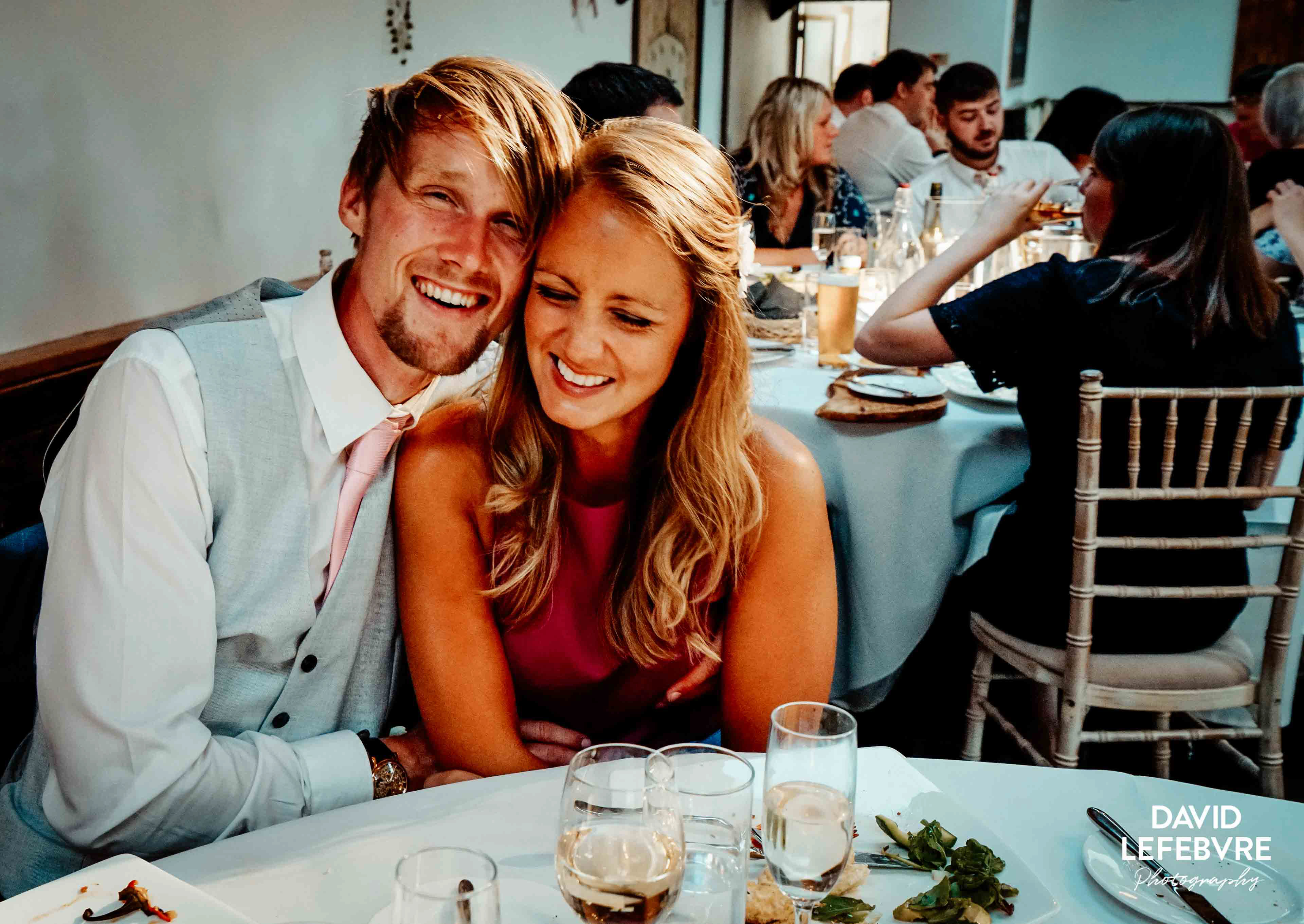 tanned couple smiling at wedding table in owen barn house