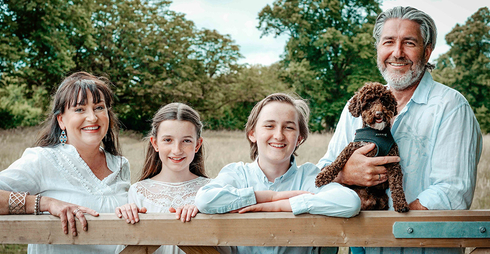 family stood at gate in wheat field in oxfordshire england near blenheim palace with portrait photographer david lefebvre