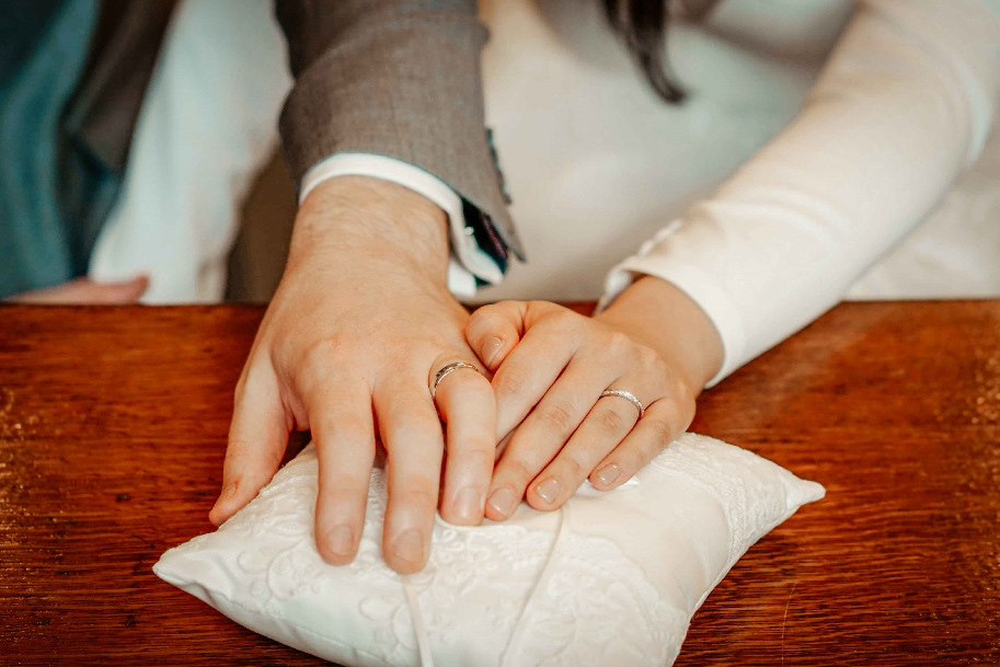 close up wedding photo by david lefebvre of bride and grooms rings on white pillow in oxford town hall
