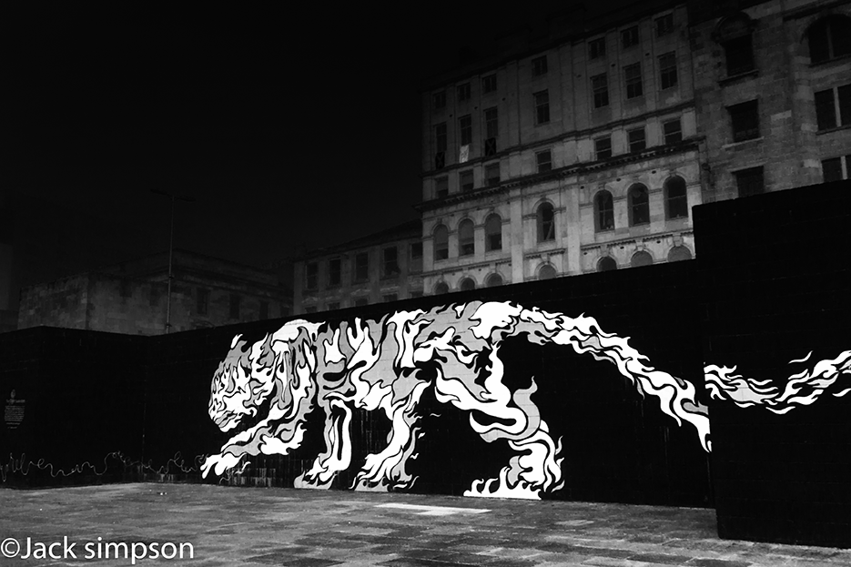 Chinese tiger painted on a wall in central Glasgow Scotland. The eye wanders from the mural to the tenement buildings behind, where from three open windows two Saltire and one Lion Rampart flags can be seen.