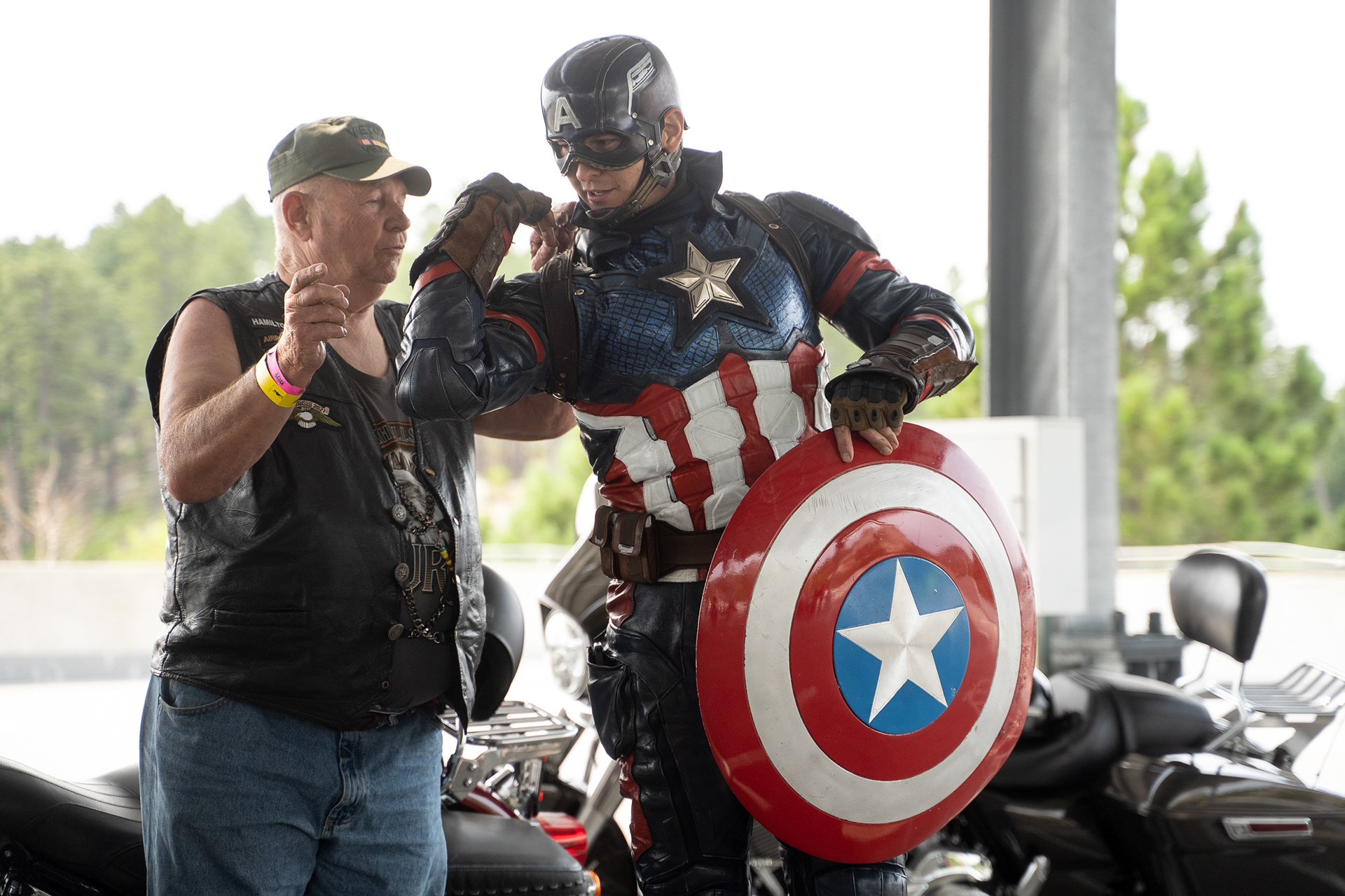 The Colorado Captain shows a fellow rider how his suit works during a stop at Mount Rushmore during the Sturgis Mayor’s ride on the second day of the 81st Sturgis Motorcycle Rally. 08.07.21.