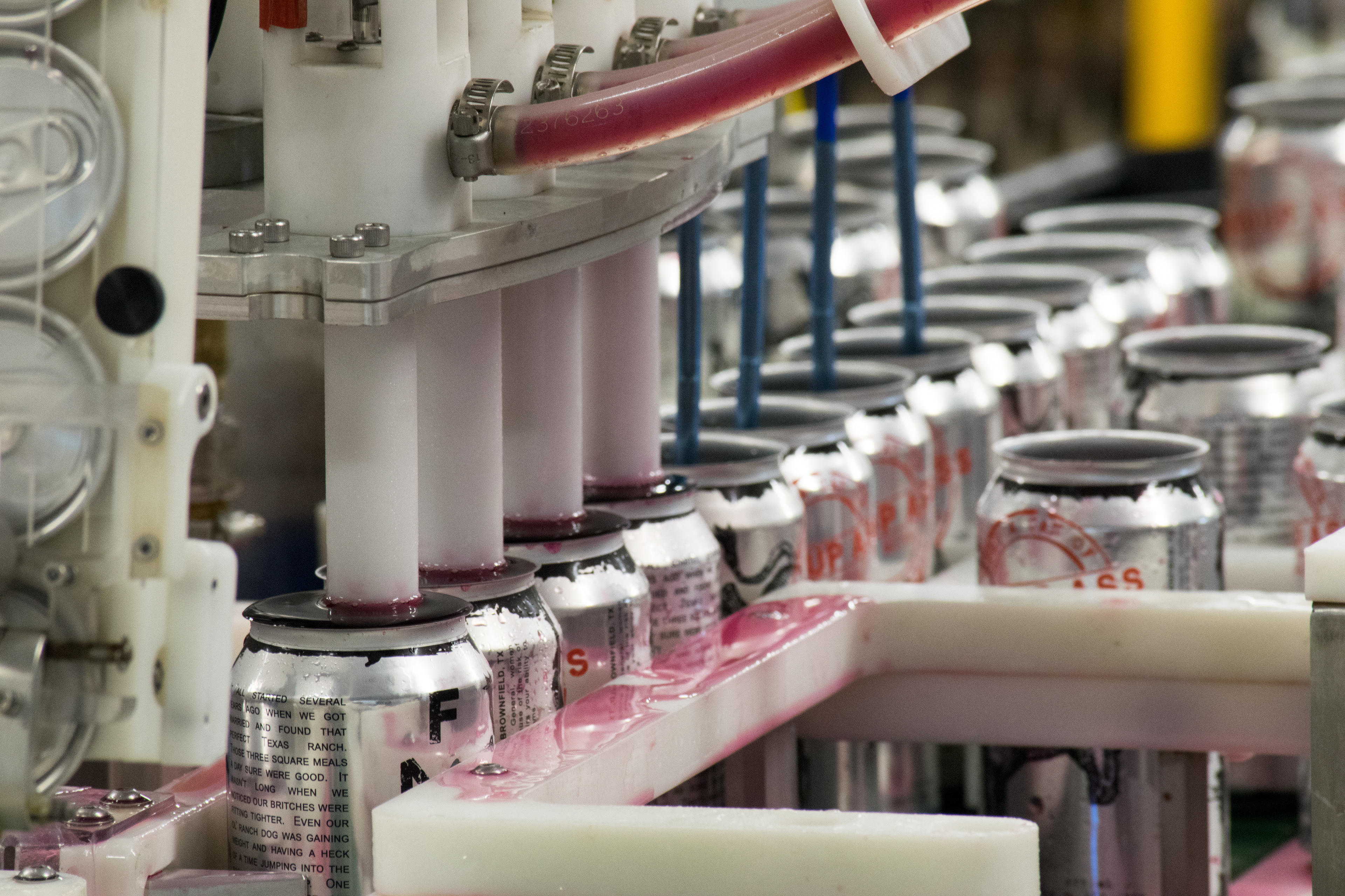 Whuup Ass cans being filled before being capped