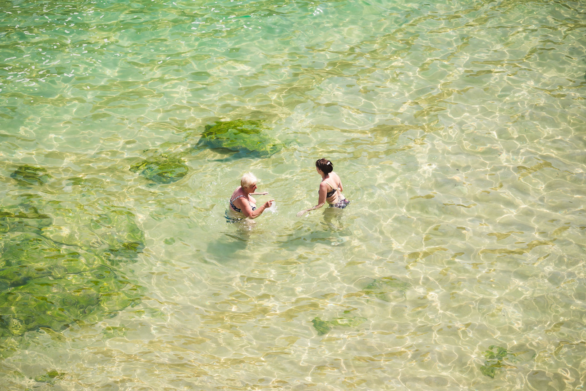 Aerial view of a womens swimming in ocean. Deep bright blue ocean.