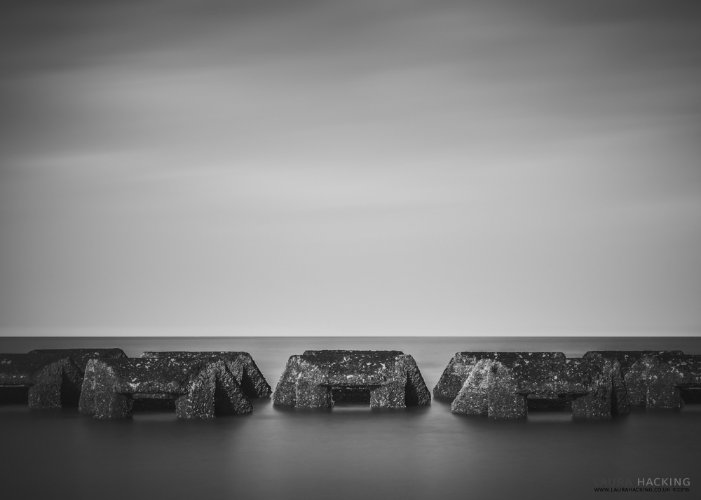 A symmetrical black and white photograph of the breakwaters at New Brighton in black and white.