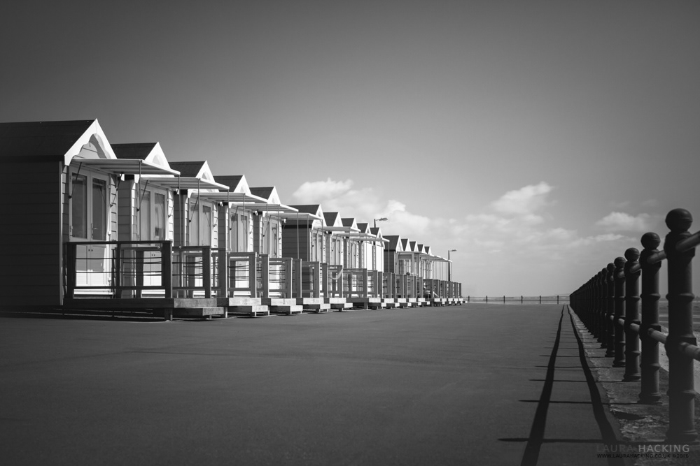 A black and white photograph of St Anne's beach huts on the promenade.