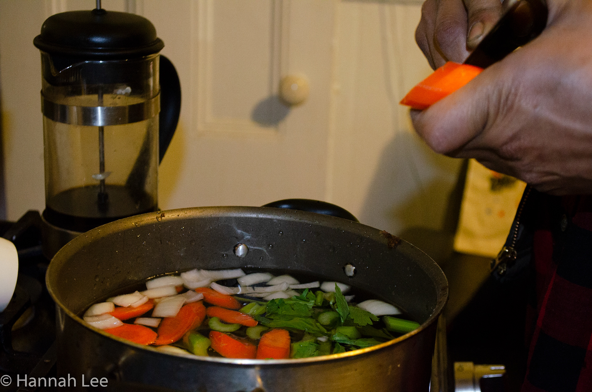 Damian makes brine with carrots, onion, celery, black pepper, bay leaf, salt, and sugar. Taken by Hannah Lee on November 25, 2020 in Somerville, MA. 1/25 second f 5.3 42mm iso 1250