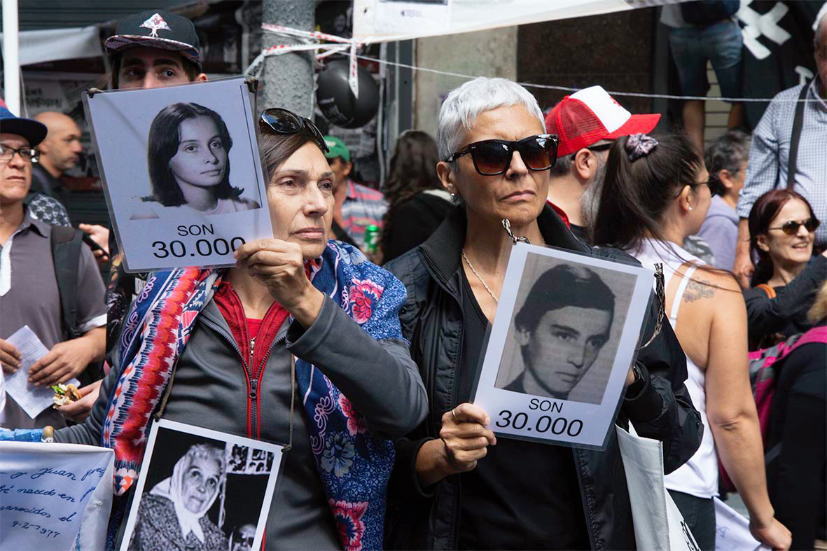 Dos mujeres sostienen fotos de desaparecidos durante la movilización al cumplirse un nuevo aniversario del golpe militar. 24/03/2019, Plaza de mayo, Buenos Aires, Argentina. Foto: Luciano Cericchio/ Argra Escuela