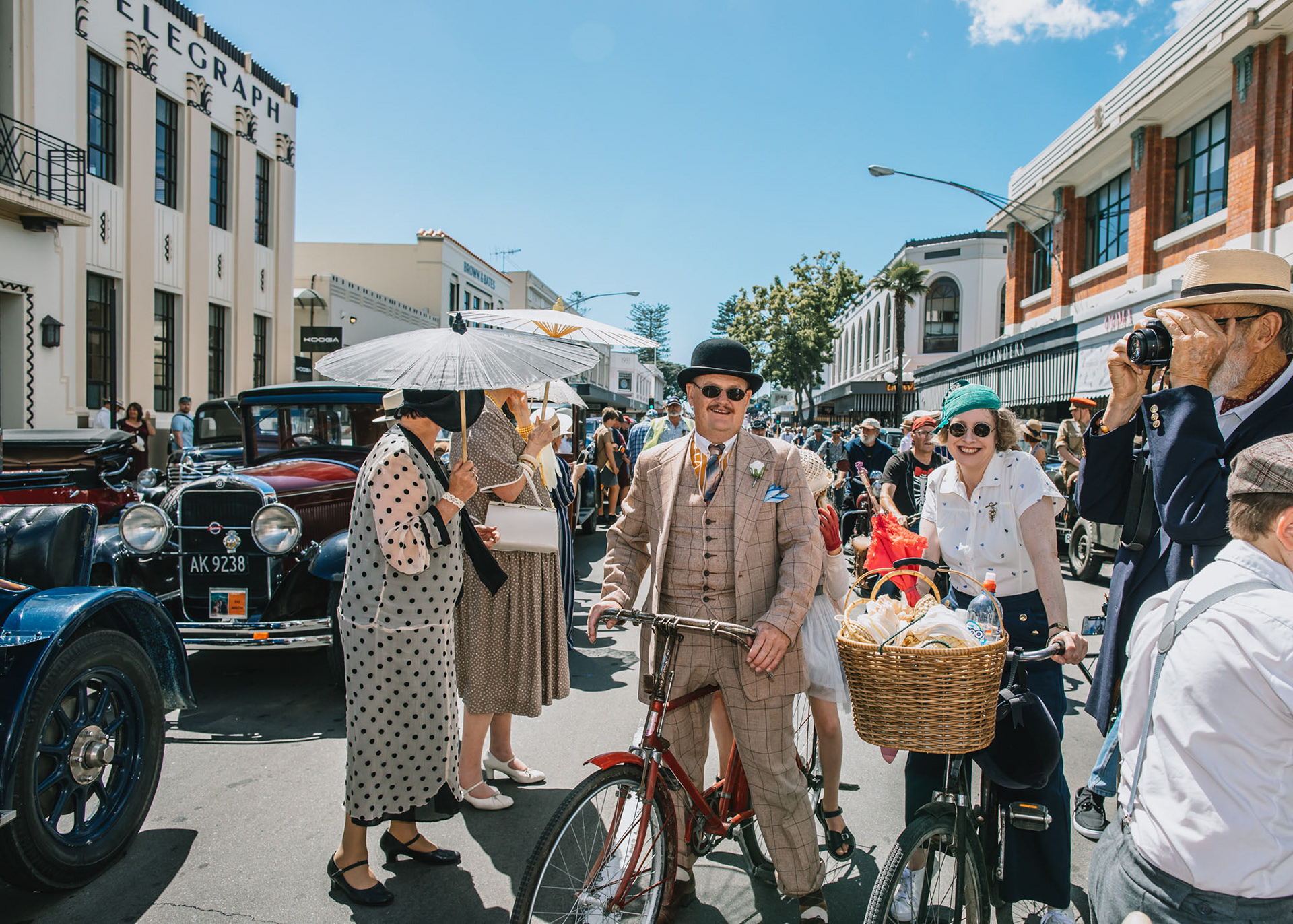 Man and woman on vintage bicycles in art deco costume on Napier city street