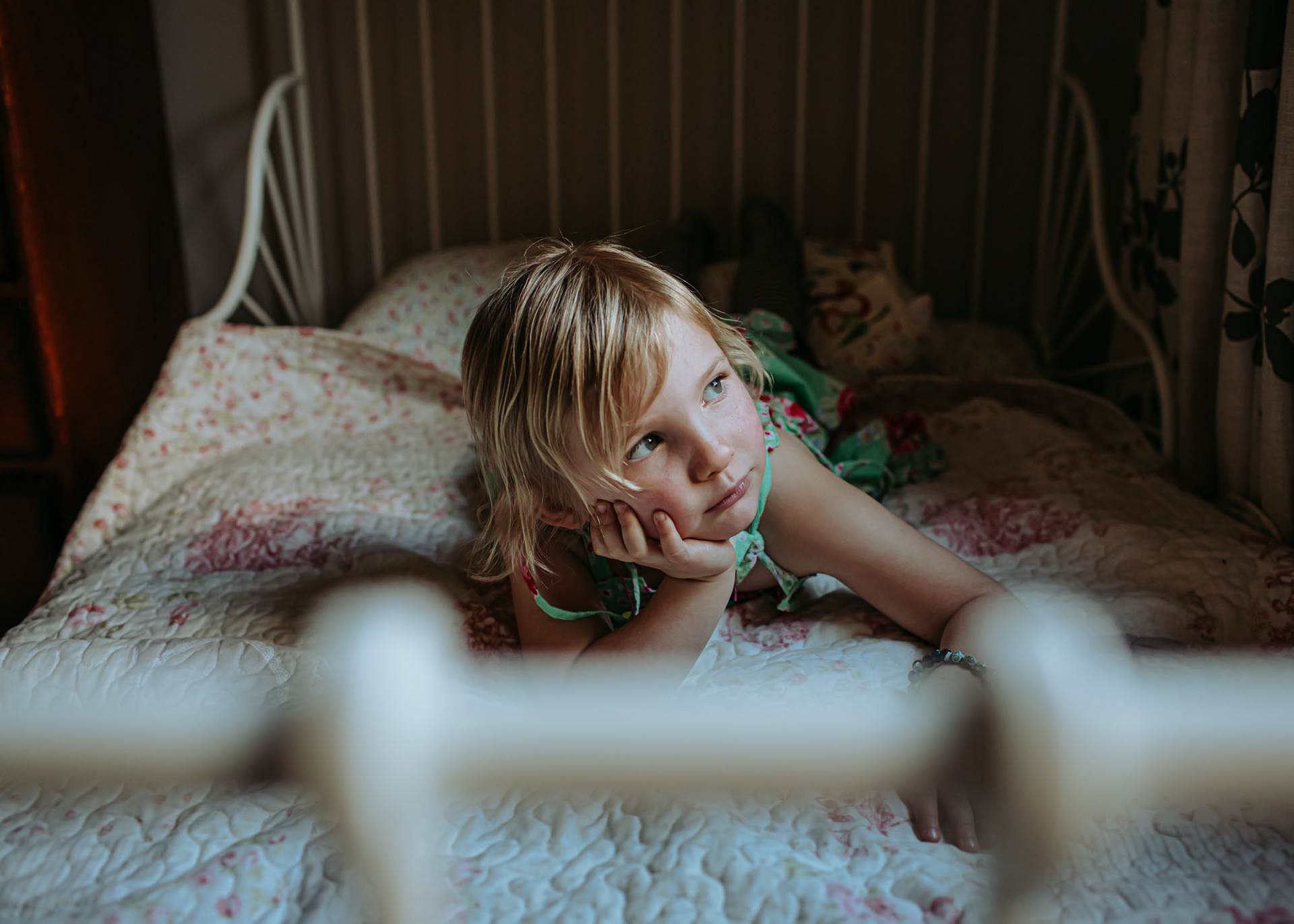 Little girl thoughtfully looking out her bedroom window