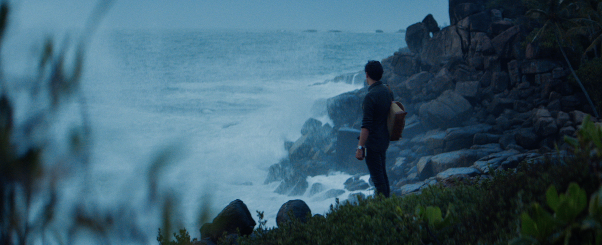 Wide shot of the hero character standing at the ocean side. Location: Sri Lanka / Asia.
