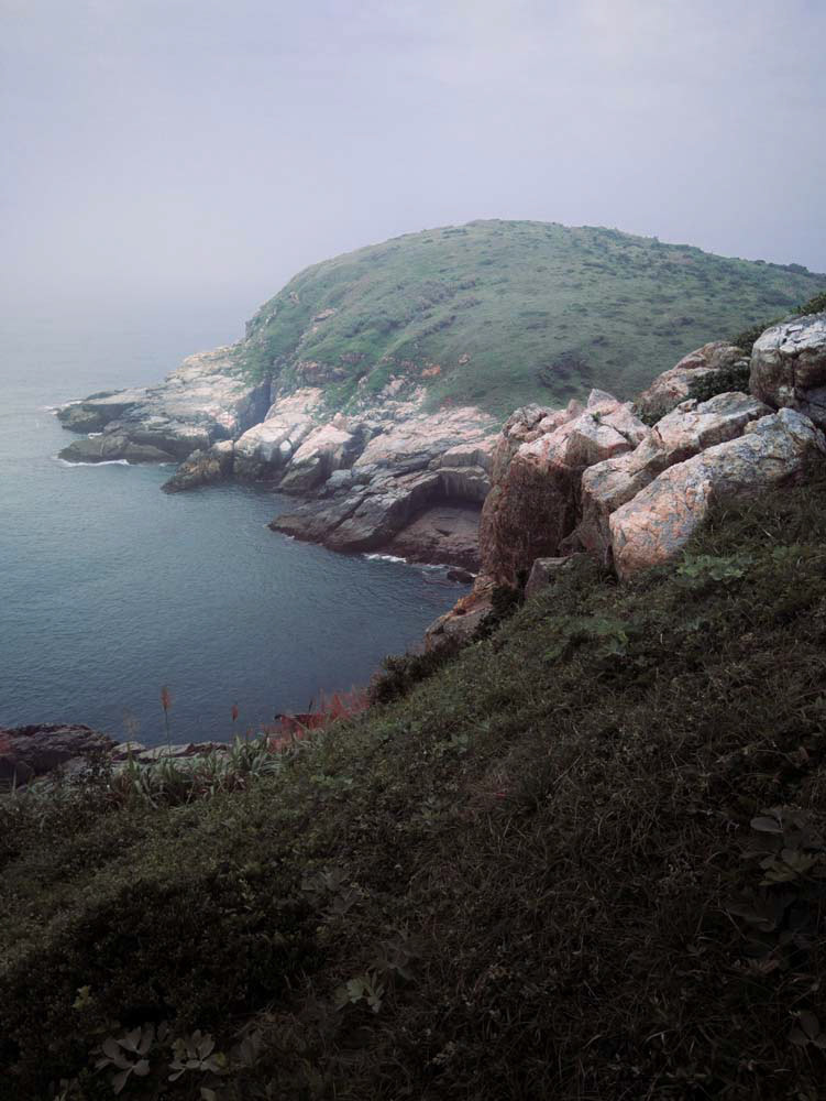 北竿鄉尼姑山俯瞰蛤蠣島。尼姑山是整座北竿島最南端的地方。而在過去的蛤蠣島怎許等待潮汐時間才能過去。這張照片中的蛤蠣島隱身在灰蒙的海岸中。實際上當年是豔陽高照卻多霧的詭異天氣
