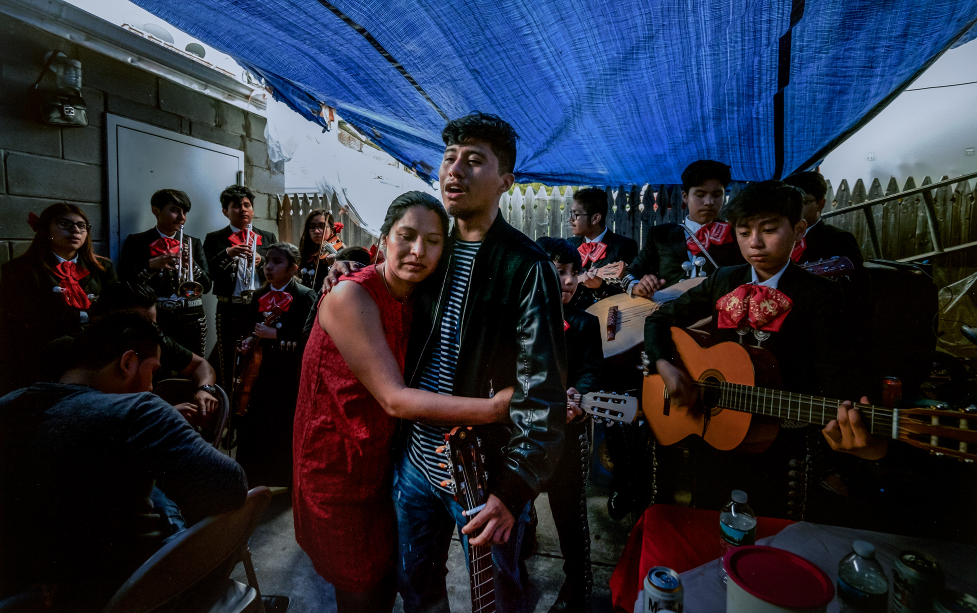 Edgar Mata, 16, a student at the Nuevo Amanecer Mariachi Academy in Queens, dedicating a song to his mother, who hugs him at a party after his confirmation ceremony. June 2017.