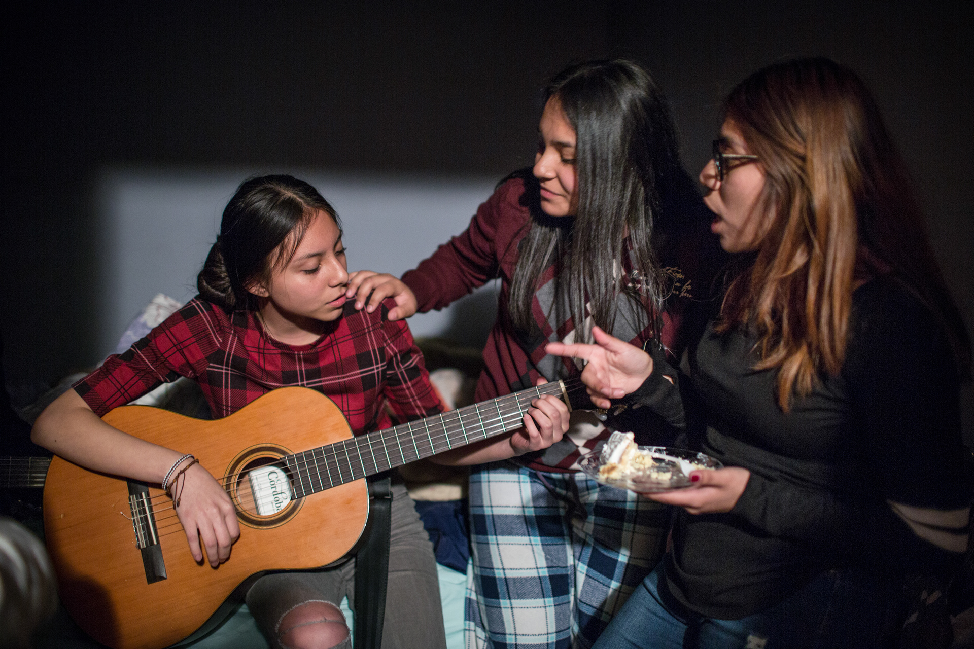 From left, Hillary Garcia, her sister, Julisa Garcia, 17, and Jenyfer Orzuna, 16, play guitar during Julisa’s birthday party. Queens, May 2017.