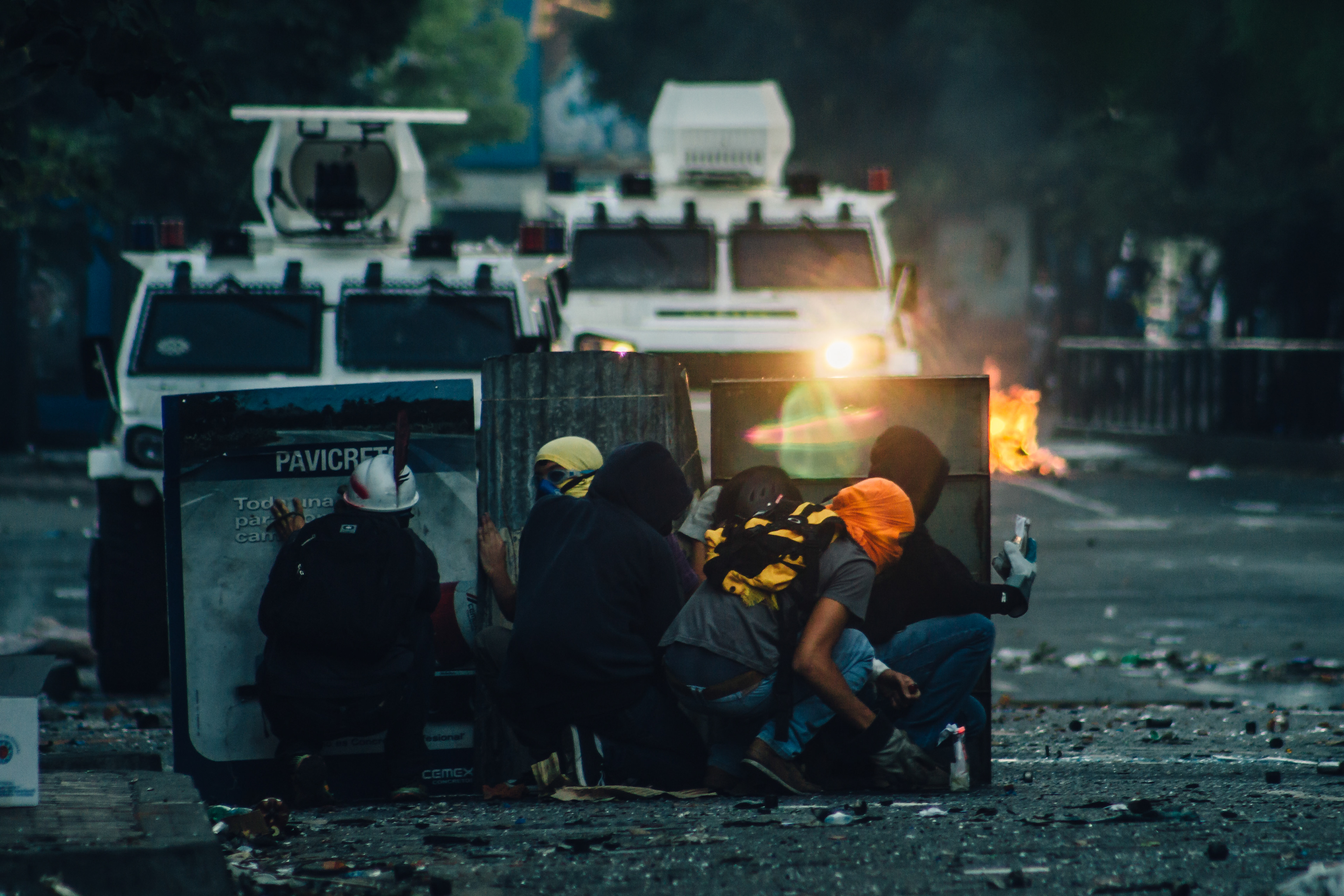 A group of protesters hide behind improvised shields as they get closer to a tank to throw Molotov cocktails at it. Caracas 2014
