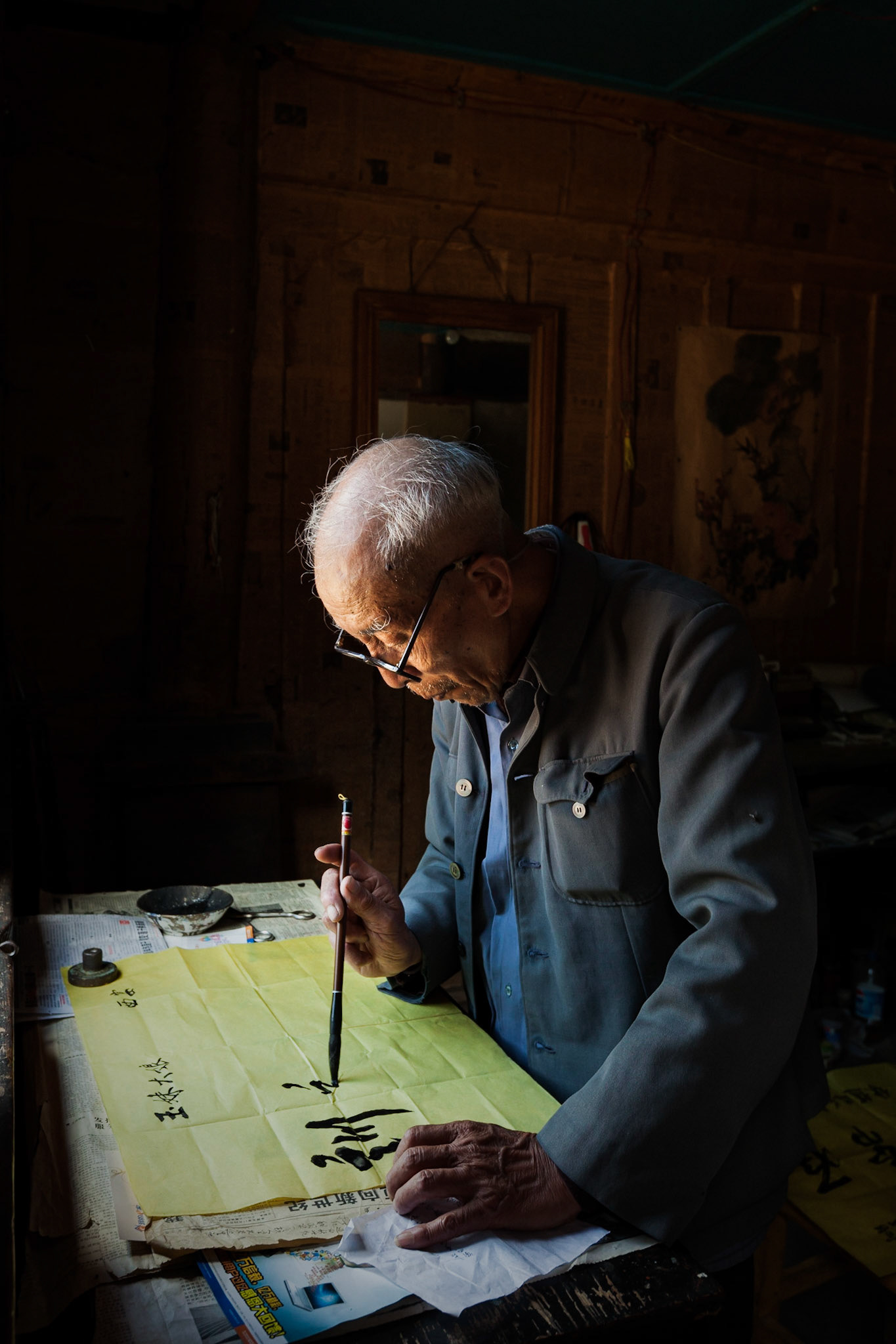 A Chinese Calligrapher making signs using traditional calligraphy in his shop in Shaxi, Yunnan Province, China.