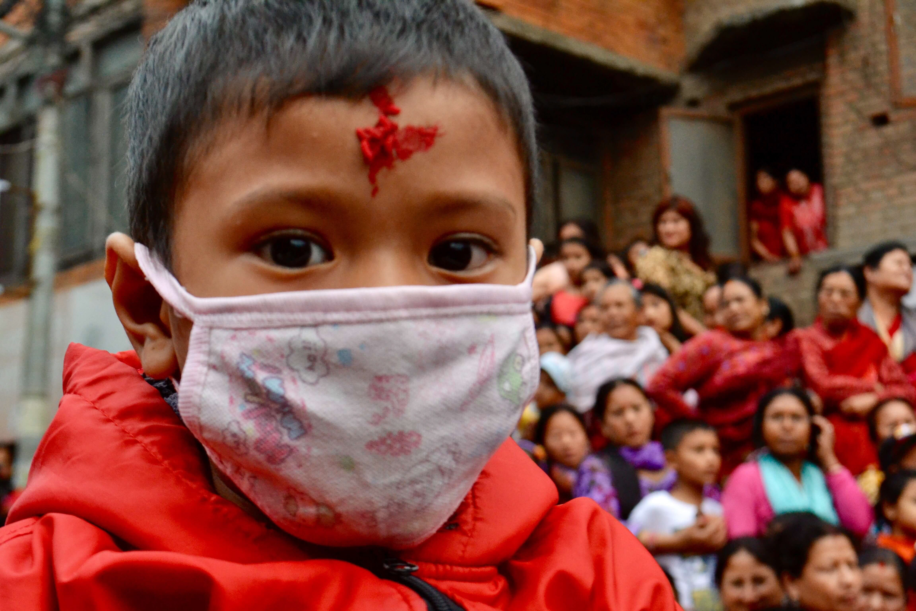 A young boy sits on the shoulders of his father to get a view of the action at the Rato Machindranath festival in Patan, Nepal