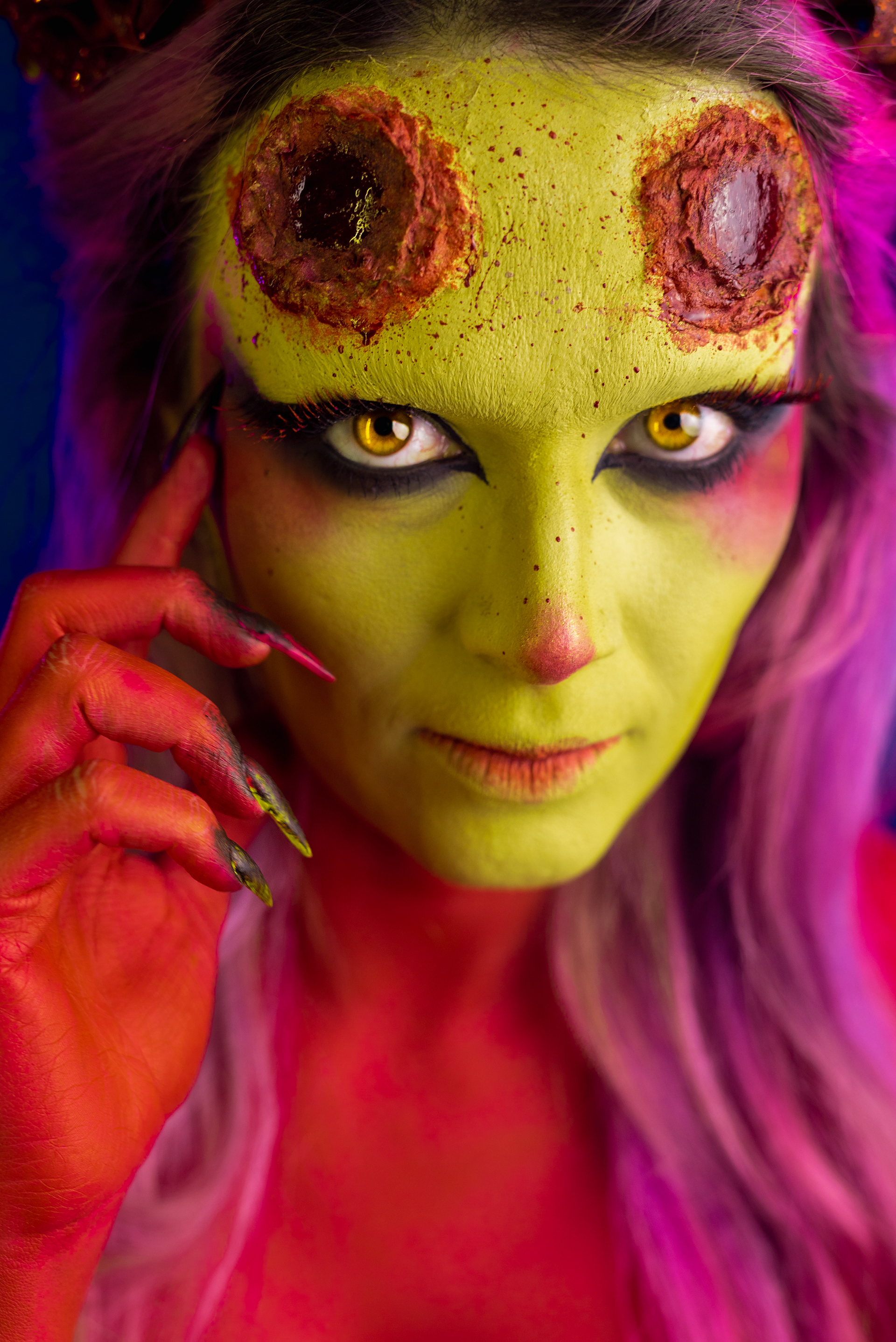 demon woman artistic makeup red skin yellow eyes on black background