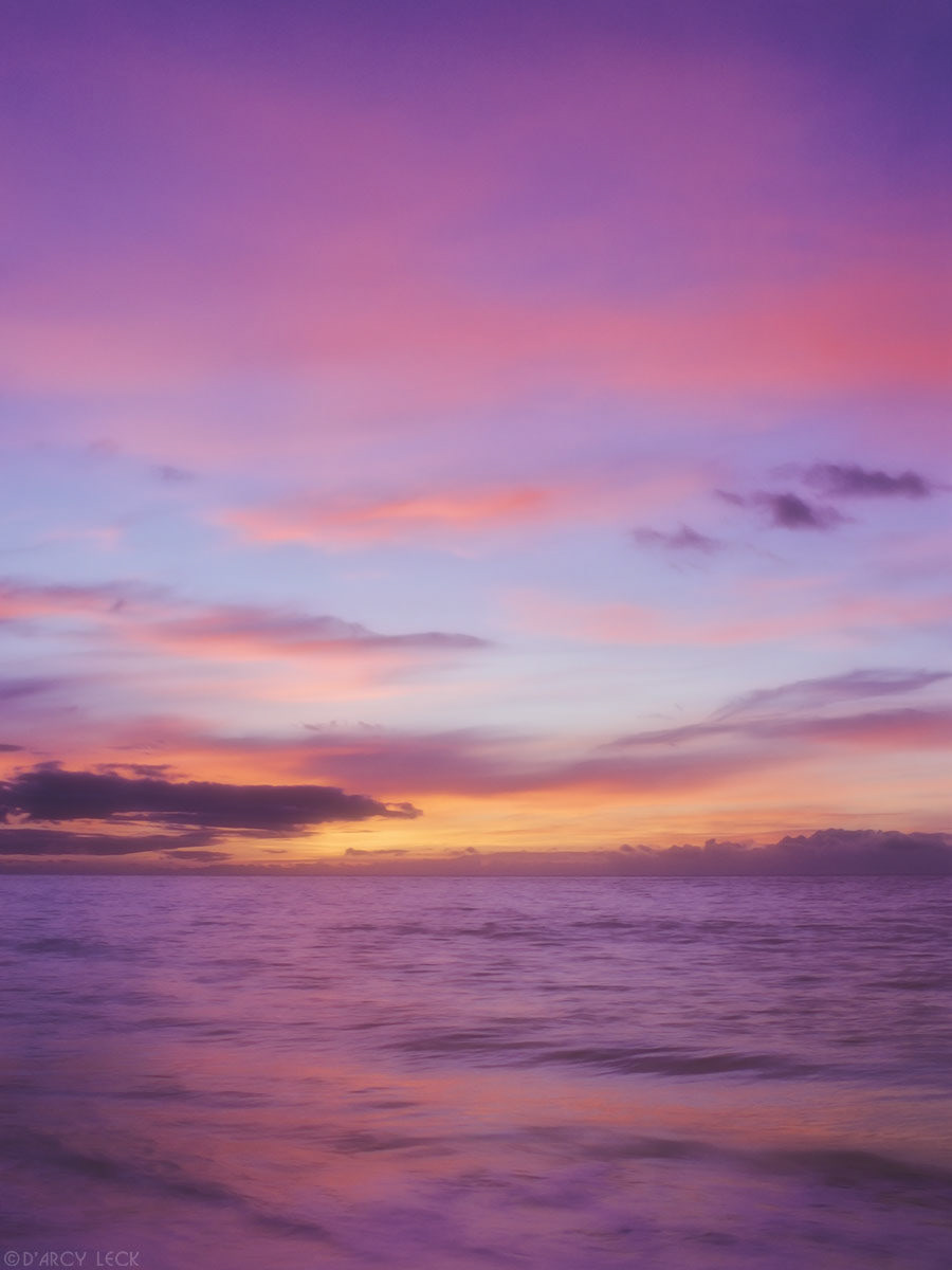 Gentle surf of Pacific Ocean rolls up sandy beach at sunset, Polihale State Park, Kauai, Hawaii
