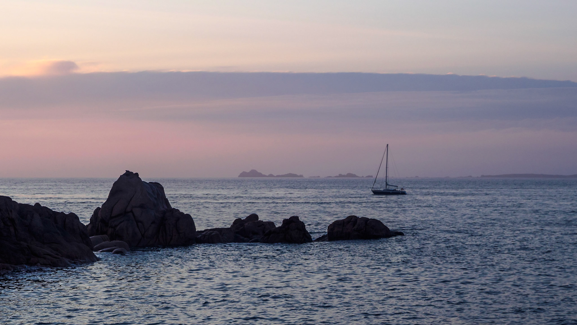As the sunlight dimmed, a small boat calmly passed us by between the pink grannite rocks in the foreground and the ilands on the horizon, ever so slightly veiled with fog.