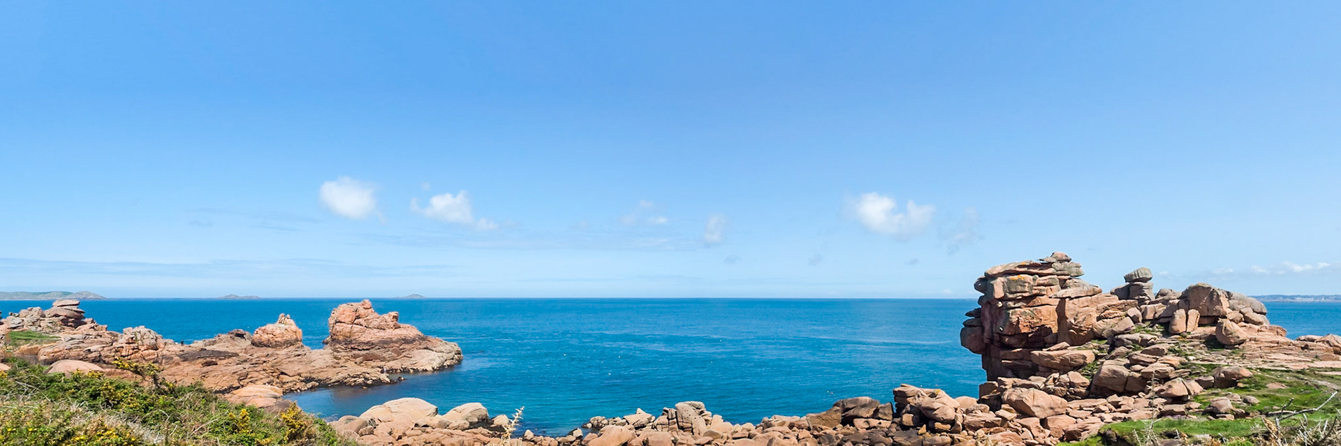 Wide scenic view from the 'Sentier des Dounaniers', endless pink granite boulders arranged by nature in the oddest compositions,  the wide blue ocean, the tranquility of the islands in the distance.