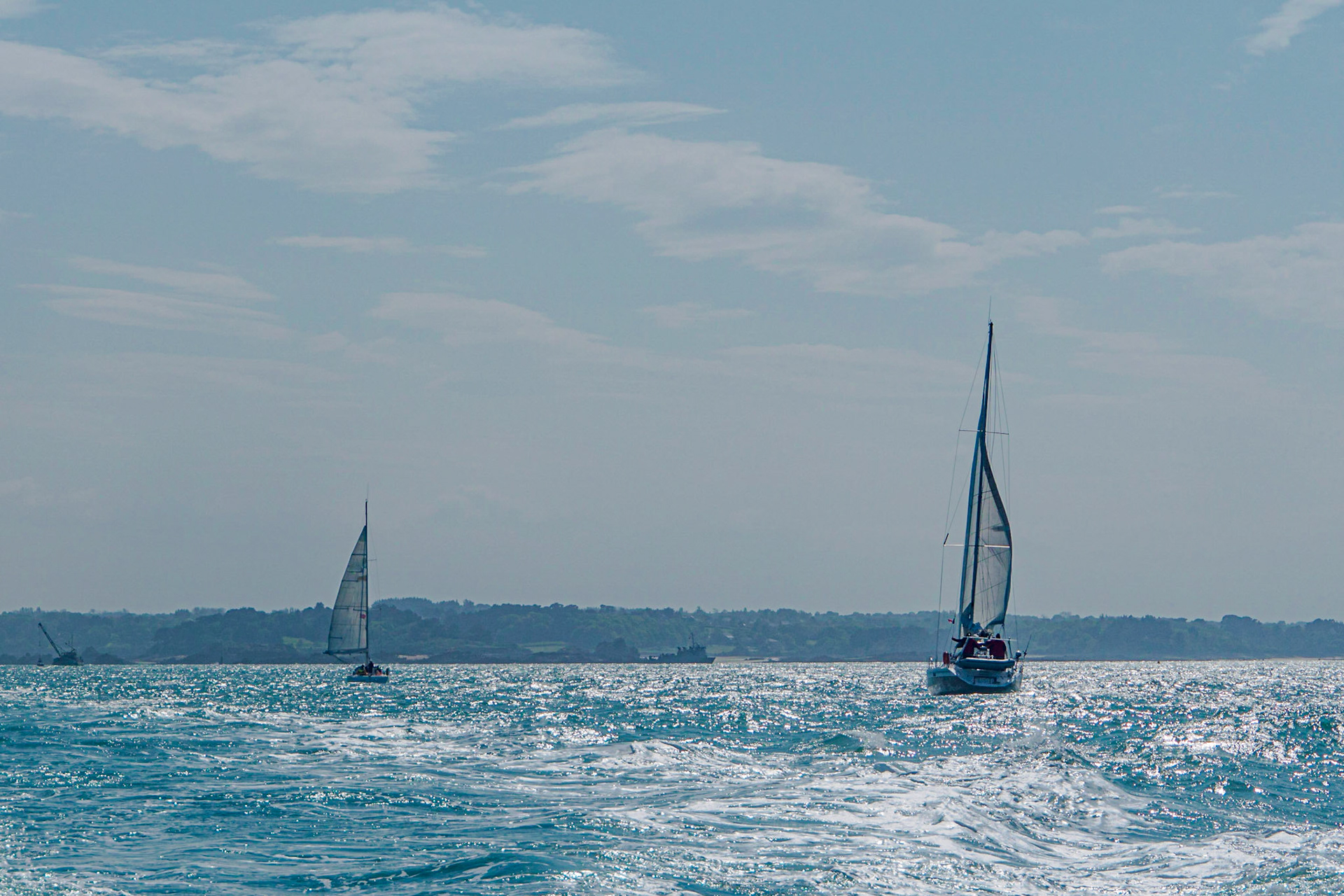 2 sailing boats off the caost of Ile de Bréhat, Bretagne, the water shimmering and glistening under the high sun.