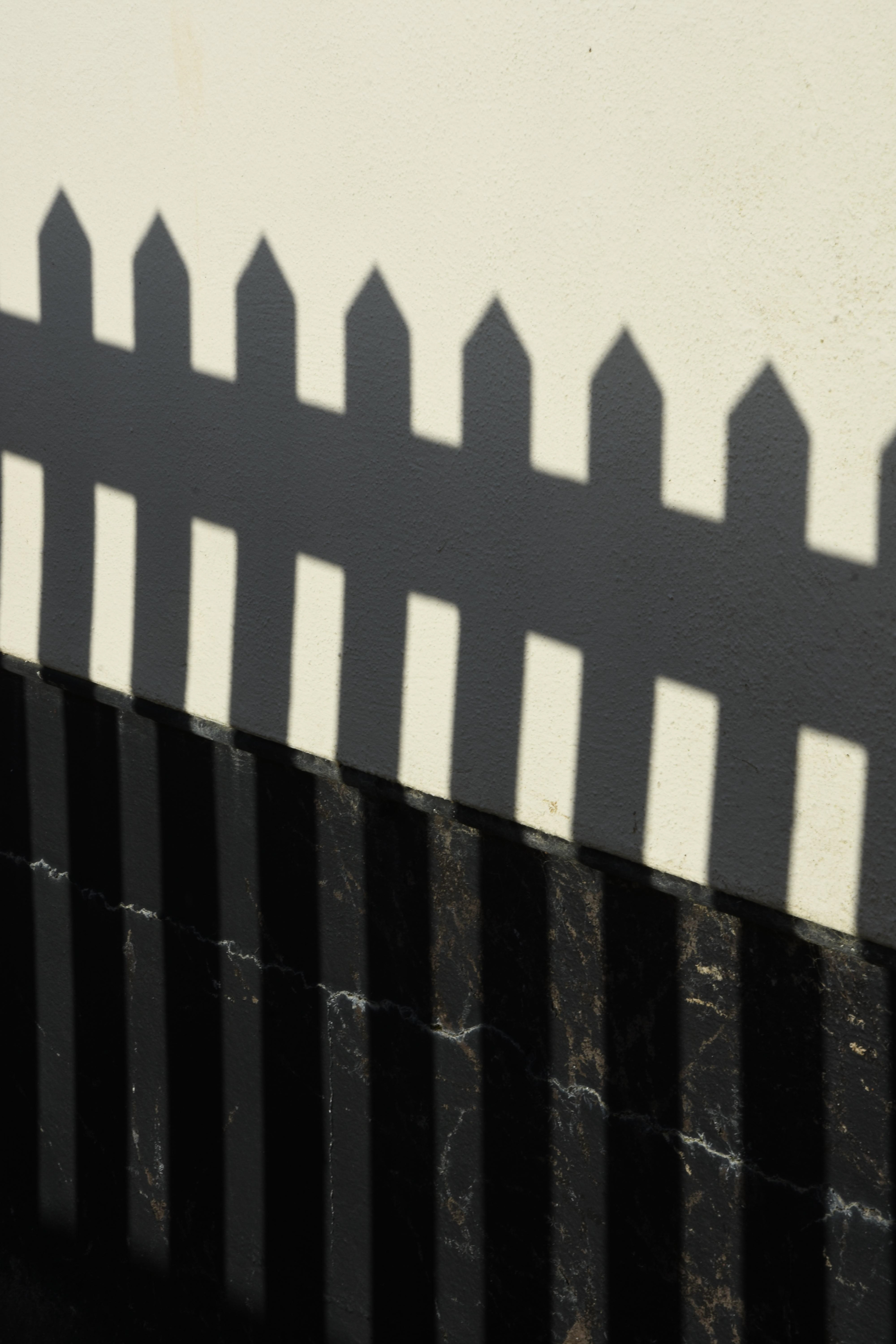 picket fence shadow on white wall documentary photography by melissa carne